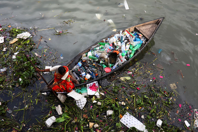 A woman collects plastic waste from the Buriganga river in Dhaka, Bangladesh, 16 September 2020.