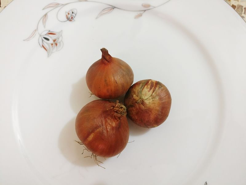 Photo shows three onions on a ceramic plate