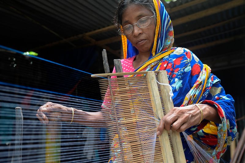 In this picture taken on 15 September 2020, a weaver prepares threads to make fabric with a handloom in Ruhitpur on the outskirts of Dhaka.