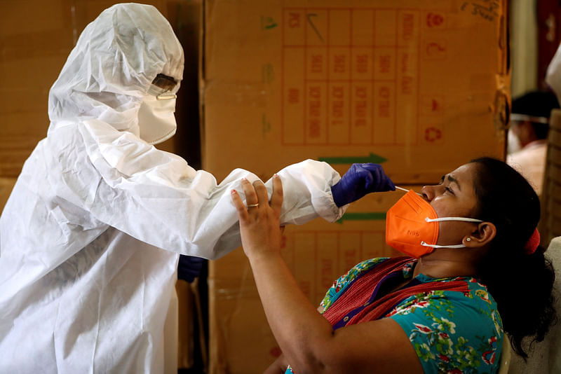 A health worker in personal protective equipment (PPE) collects a swab sample from a woman during a rapid antigen testing campaign for the coronavirus disease (COVID-19) in Mumbai, India, 7 September 2020.