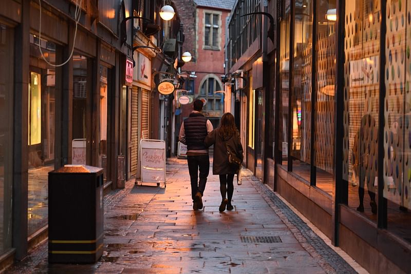 A couple walk past closed shops in a quiet lane in central Sheffield, in northern England on 21 October 2020, prior to further lockdown measures to combat the rise in novel coronavirus COVID-19 cases. More than a million people in northern England will be banned from mixing with other households under tougher new coronavirus rules announced by government minister Robert Jenrick on Wednesday