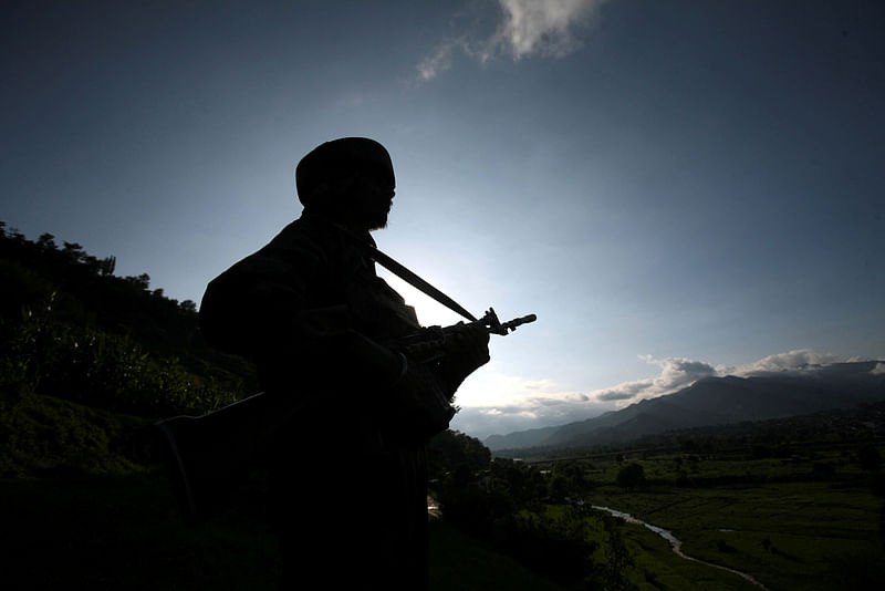 An Indian army soldier stands guard while patrolling near the Line of Control, a ceasefire line dividing Kashmir between India and Pakistan, in Poonch