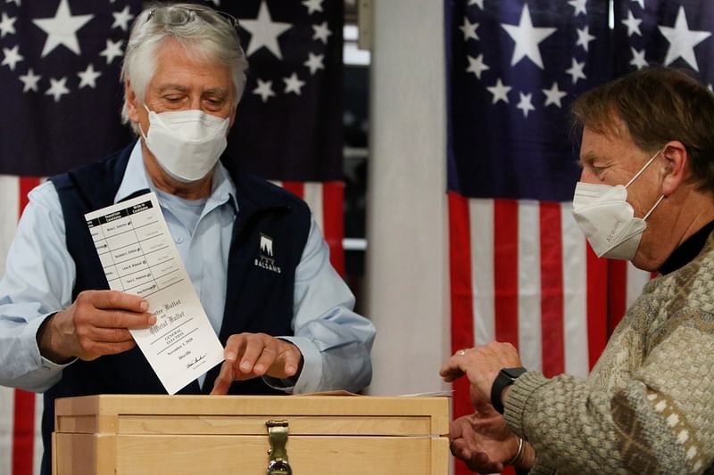 Selectman Les Otten drops a ballot in a box shortly after midnight for the US presidential election at the Hale House at Balsams Hotel in the hamlet of Dixville Notch, New Hampshire US 3 November 2020.