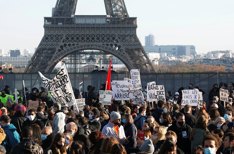 Demonstrators hold up placards in front the Eiffel Tower during a protest against a bill that would make it a crime to circulate an image of a police officer's face, at Trocadero square, in Paris, France, on 21 November 2020