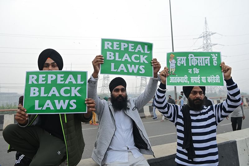 Farmers hold placards during a protest march against the recent agricultural reforms, along a road blocked by police at the Delhi-Uttar Pradesh state border in Ghazipur on 12 December 2020