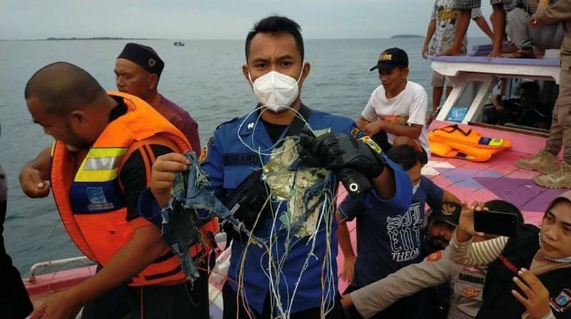 A member of the rescue team looking for an Indonesian plane that lost contact after taking off from the capital Jakarta holds suspected debris, at sea, 9 January, 2021, in this picture obtained from social media