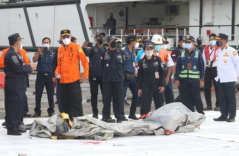 Rescue workers inspect recovered debris at the port in Jakarta on 10 January 2021, during the search operation for Sriwijaya Air flight SJY182 which crashed after takeoff from Jakarta on 9 January