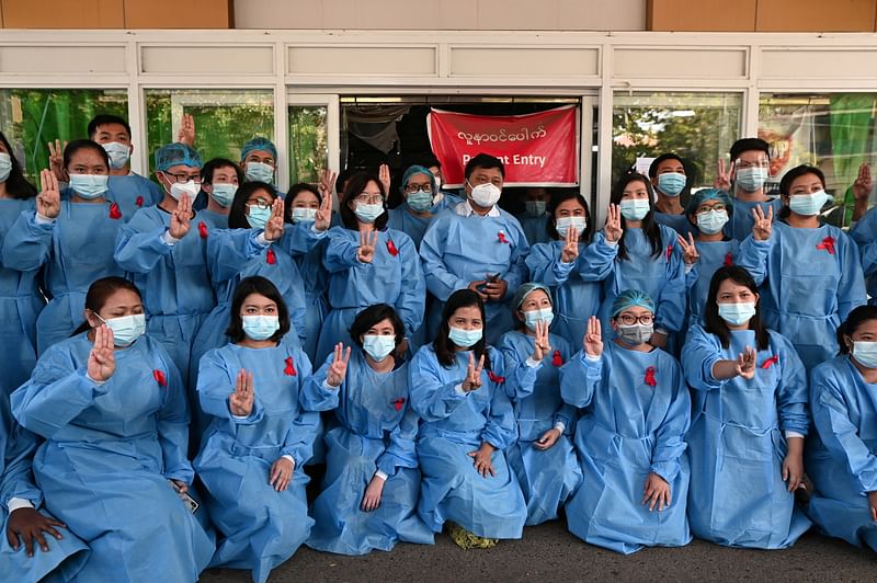 Medical workers wearing red ribbons pose during a protest against the coup that ousted elected leader Aung San Suu Kyi, in Yangon General Hospital in Yangon, Myanmar on 3 February 2021