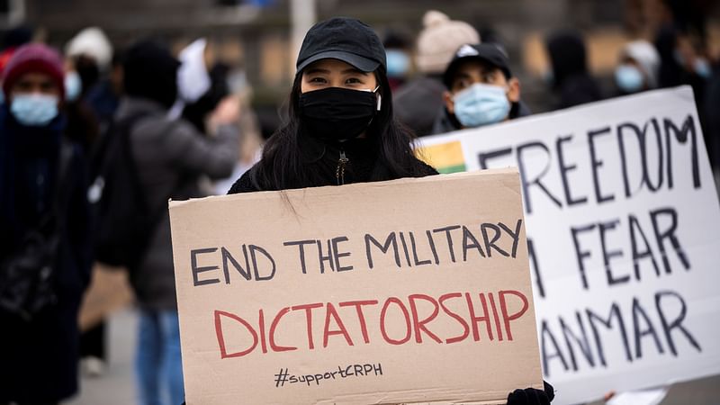 A woman holds a placard during a protest against the military coup in Myanmar, at Town Hall Square in Copenhagen, Denmark, on 13 March 2021