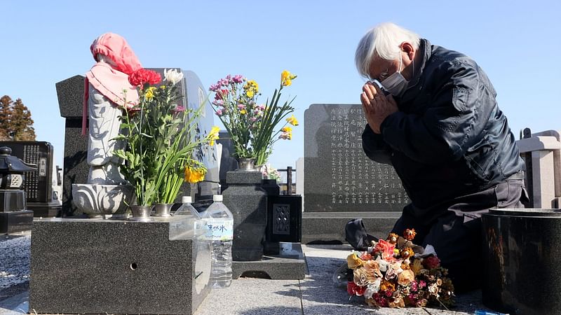 A Local resident who lost his daughter pays a respect at a cemetery in Namie, Fukushima prefecture on 11 March 2021, the 10th anniversary of the 9.0 magnitude earthquake which triggered a tsunami and nuclear disaster