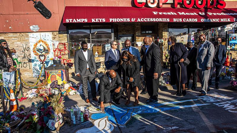 George Floyd's brother Philonise Floyd (C) kneels, flanked by family members, at a memorial at the site where his brother died while being arrested, after attending a press conference on 12 March 2021 in Minneapolis, Minnesota