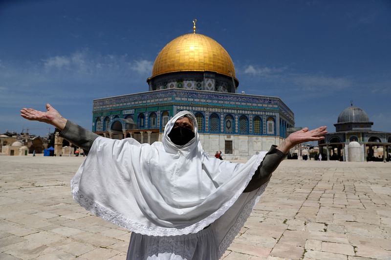 A Palestinian woman raises her arms in prayer as she takes part in the first Friday prayers of the Muslim fasting month of Ramadan, outside the Dome of the Rock at the Al-Aqsa Mosque compound, Islam's third holiest site, in Jerusalem's Old City, on 16 April, 2021