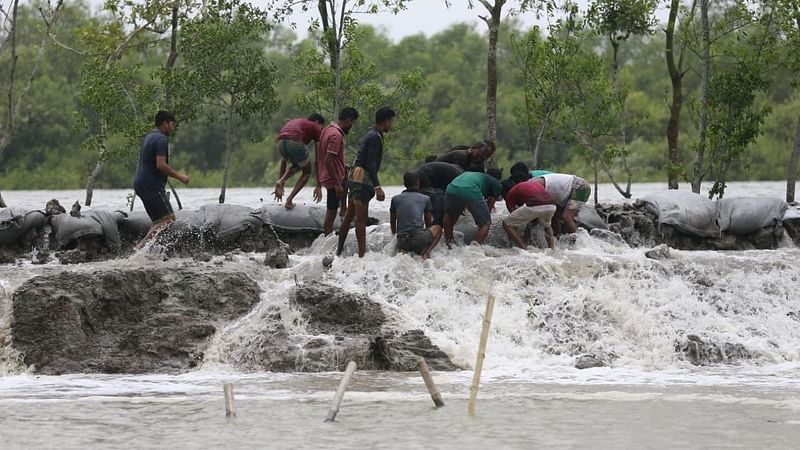 People working to strengthen washed away dams with sand-filled geo bags as tide water of Chuna river enters locality in Burigoalini area of Shyamnagar upazila, Satkhira on 26 May 2021