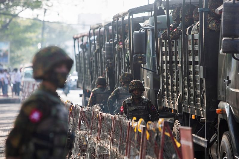 Soldiers stand next to military vehicles as people gather to protest against the military coup, in Yangon, Myanmar on 15 February 2021.