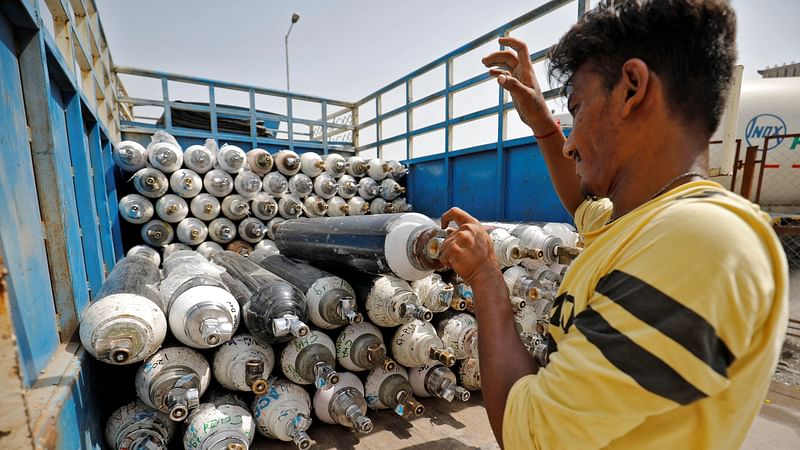 A worker loads empty oxygen cylinders onto a supply van to be transported to a filling station, at a Covid-19 hospital, amidst the spread of the coronavirus disease