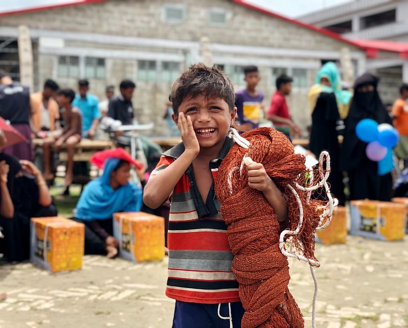 The government distributed livelihood materials among Rohingyas in Bhasan Char on Friday. Ziaur Rahman's seven-year-old son is elated with the fishing net given to his father.