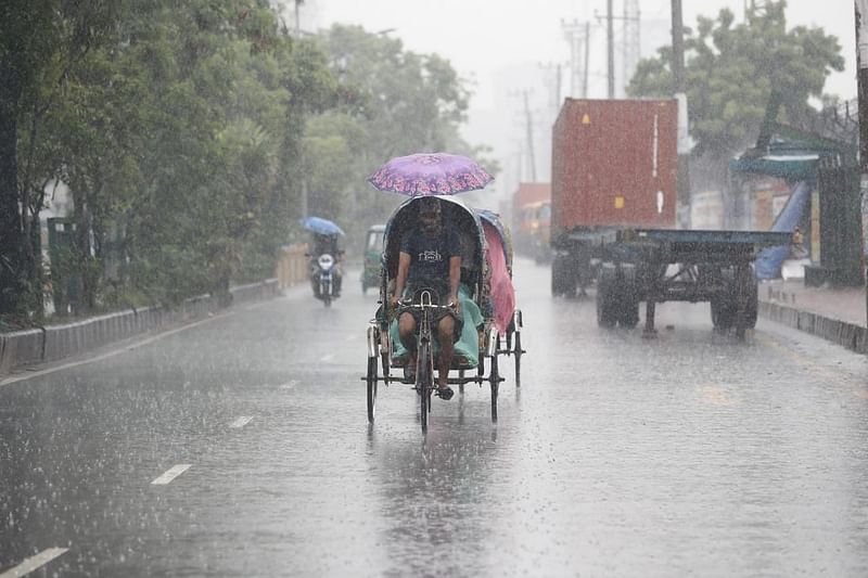 A rickshaw-puller with his rickshaw in torrential rains in Dhaka