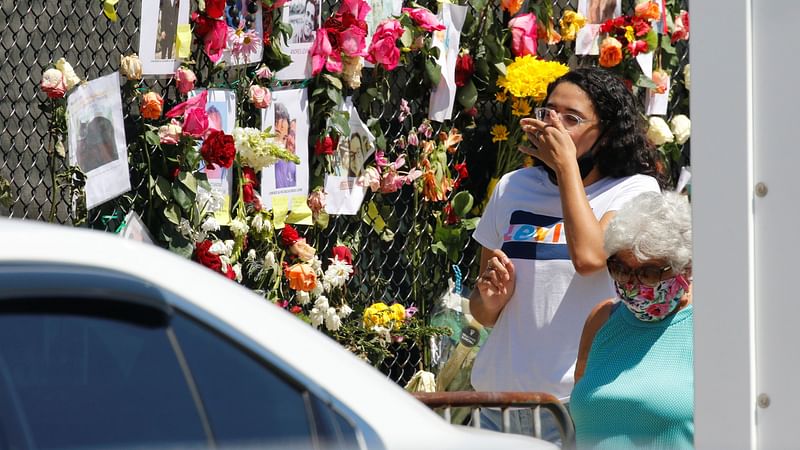 Visitors react at a memorial near the site of a partially collapsed residential building in Surfside, near Miami Beach, Florida, US on 27 June 2021