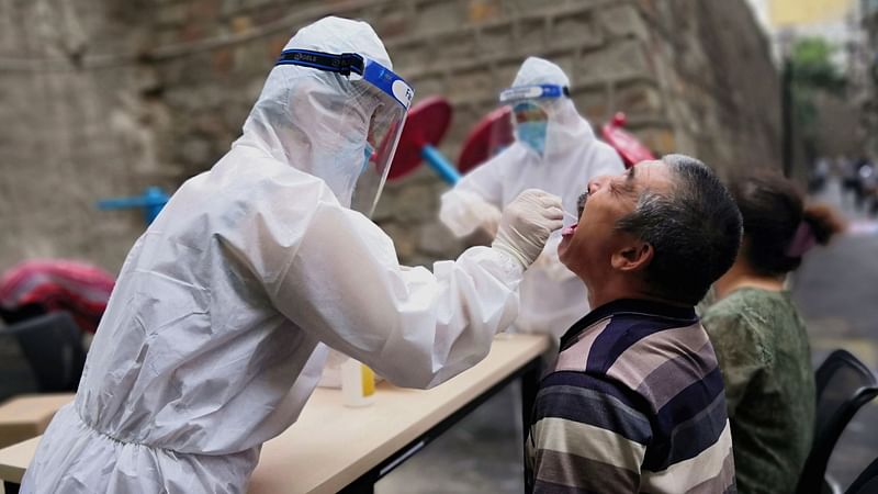 A medical worker in protective suit collects a swab from a man to conduct free nucleic acid tests for residents in the residential compound, after new cases of coronavirus disease (Covid-19) were found in Urumqi, Xinjiang province, China on 19 July.