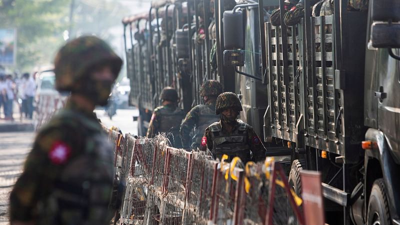 Members of Myanmar Army stand next to military vehicles as people gather to protest against the military coup, in Yangon, Myanmar, on 15 February, 2021