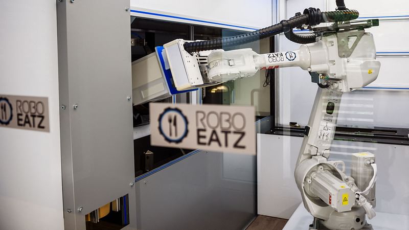 A photo taken on 25 May 2021 shows a robot seen behind a screen as it prepares food at the Roboeatz eatery in Riga. A pasta order comes in and the robotic arm springs into action at the Roboeatz eatery in Riga.