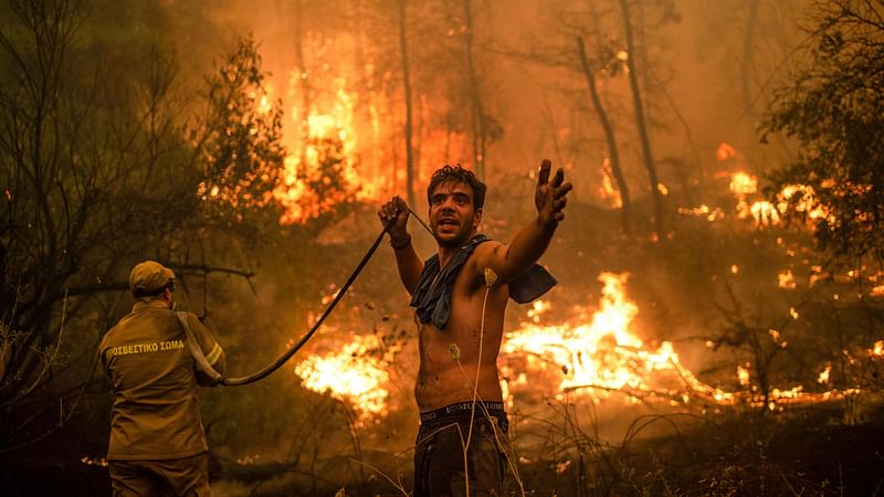 A local resident gestures as he holds n empty water hose during an attempt to extinguish forest fires approaching the village of Pefki on Evia (Euboea) island, Greece's second largest island, on 8 August 2021.