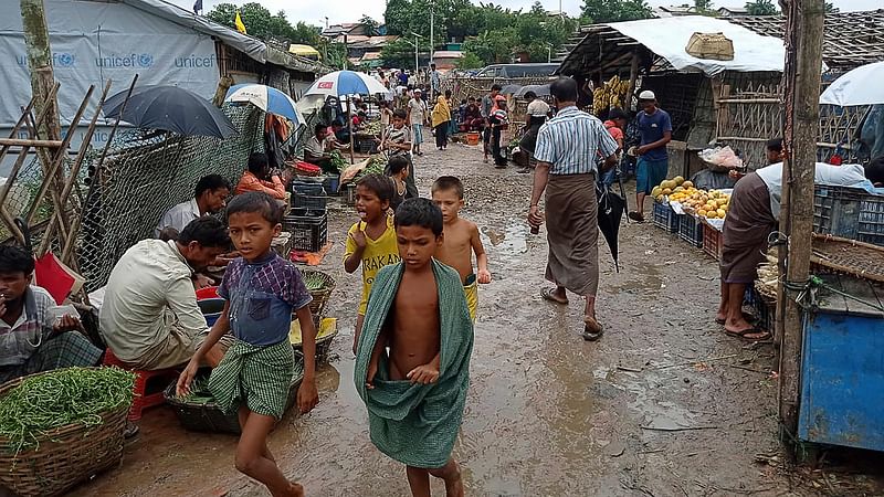 Rohingya refugees walk along a path at Kutupalong refugee camp in Ukhia on 25 August 2021