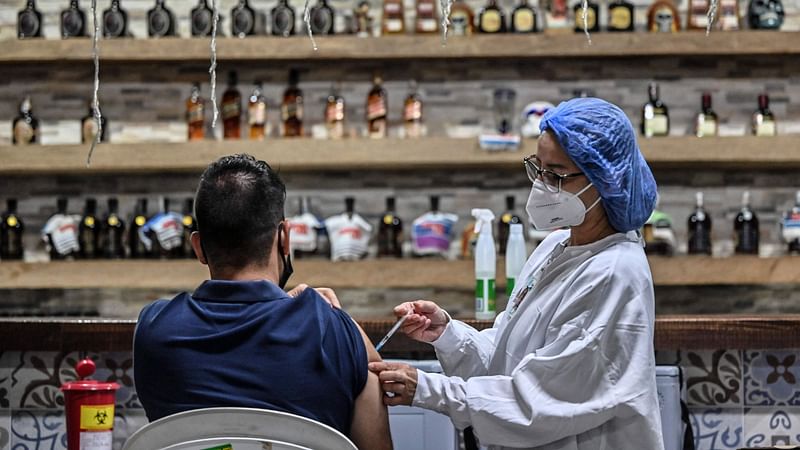 A nurse gives a dose of the Moderna vaccine against COVID-19 to a man at a vaccination point in the La Cantina bar in Medellin, on 11 August 2021