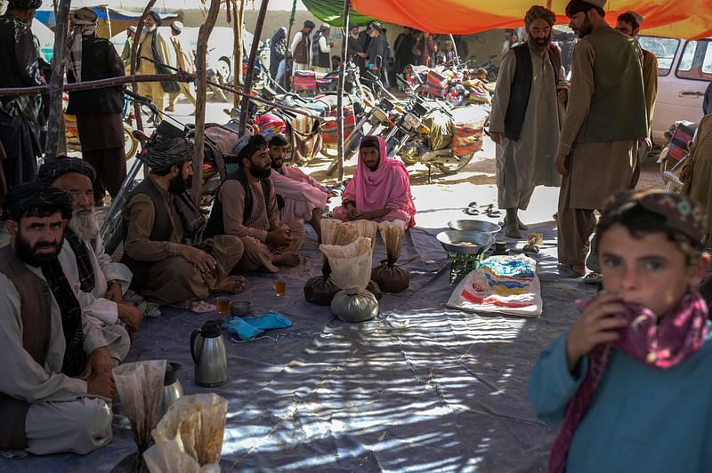 In this picture taken on September 24, 2021, men gather around bags containing heroin and hashish as they negotiate and check quality at a drug market on the outskirts of Kandahar