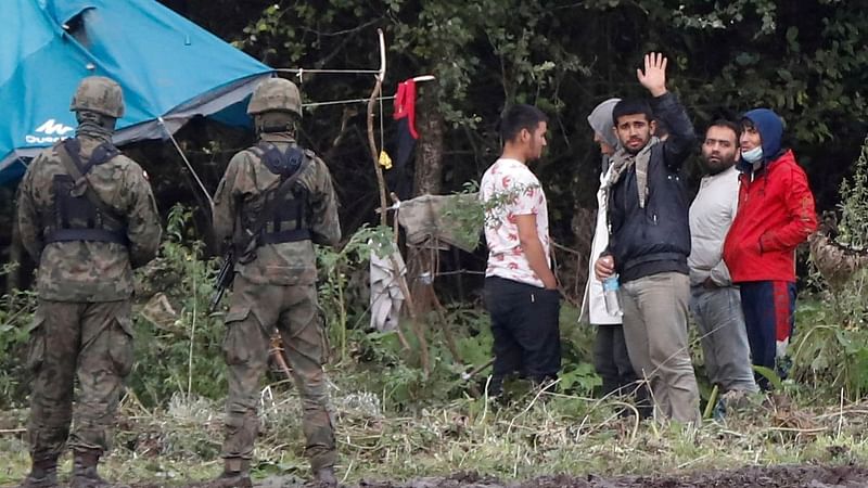 Polish border guard officers stand guard next to a group of migrants stranded on the border between Belarus and Poland near the village of Usnarz Gorny, Poland on 1 September, 2021