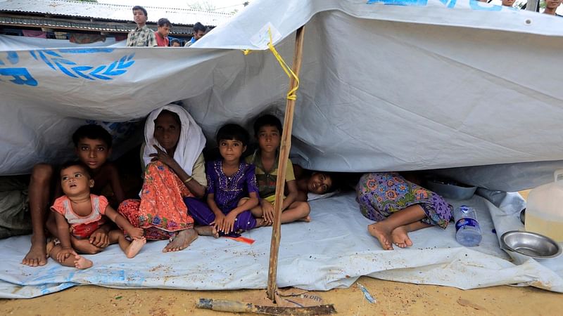 Refugee children from Myanmar sit outside a school used as a shelter