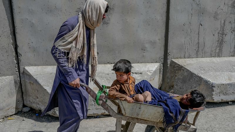 A man pulls children on a wheelbarrow as they rush to pass to Pakistan from the Afghanistan border in Spin Boldak on 25 September 2021