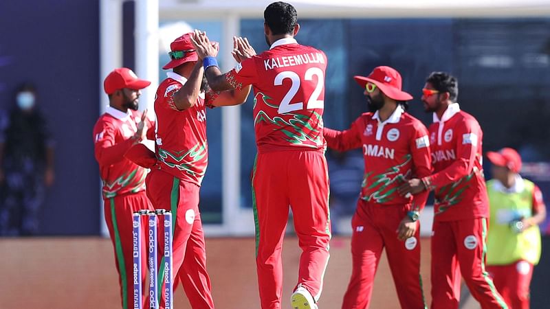 Oman's Kaleemullah (C) celebrates with his teammates after taking the wicket of Papua New Guinea's captain Assad Vala (not pictured) during the ICC men’s Twenty20I World Cup cricket match between Oman and Papua New Guinea at the Oman Cricket Academy Ground in Muscat on 17 October, 2021