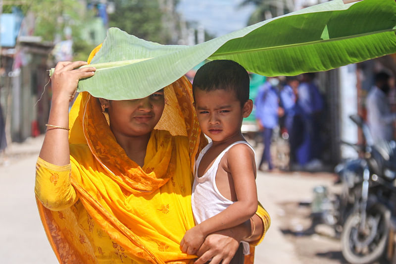 A mother tries to save her child from scorching heat. The picture was taken from Bastuhara in Khulna