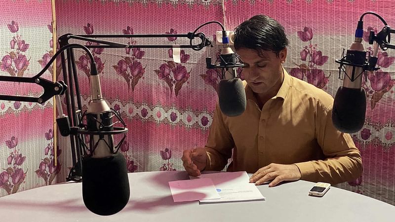 In this photograph taken on 12 October, 2021, radio presenter Ebrahim Parhar reads the news during a broadcast at radio station Urooj in Farah province of Afghanistan