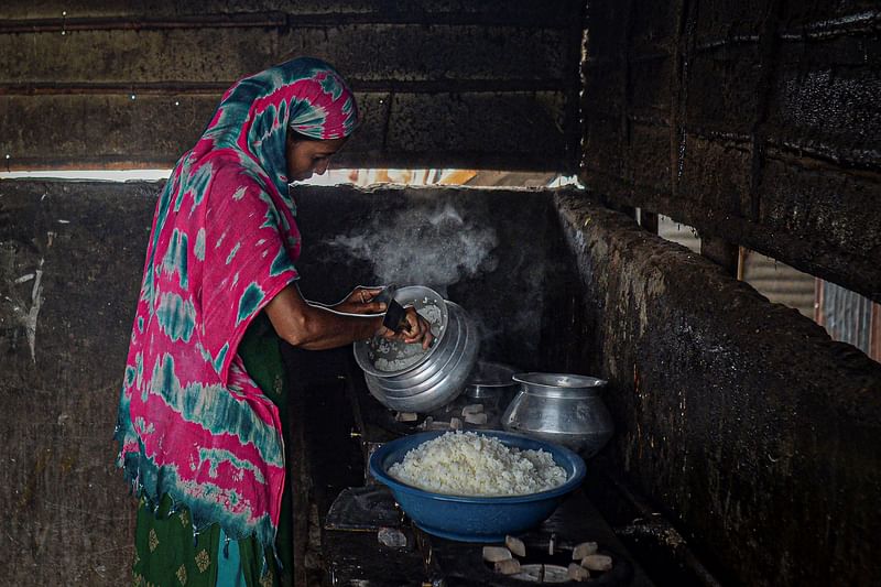 A woman cooks a meal in a shanty settlement in Dhaka