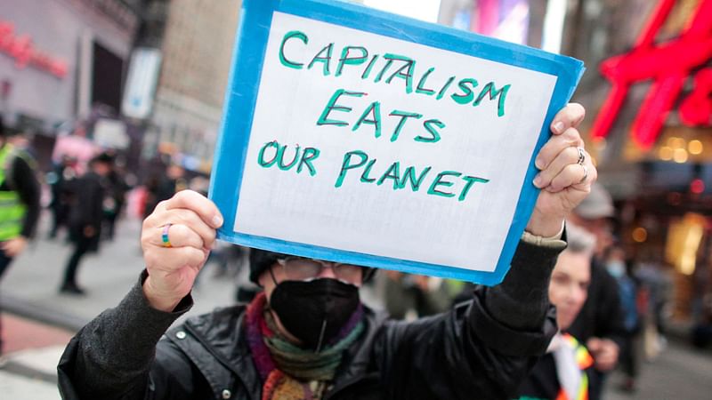 A protestor holds a sign reading "Capitalism Eats Our Planet" during the Climate Justice March from Times Square to Governor Hochul's Manhattan office in New York on 13 November 2021