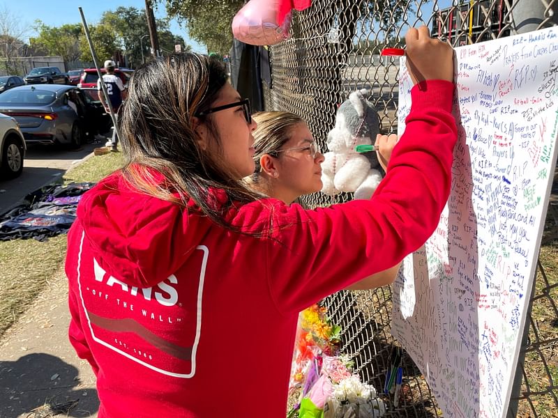 Daniella Salazar, 23, of Corpus Christi, and Celeste Salinas, 23, of Houston, sign a remembrance poster at a makeshift memorial for the concertgoers who died in a stampede at the 2021 Astroworld Festival in Houston, Texas, U.S. 7 November, 2021