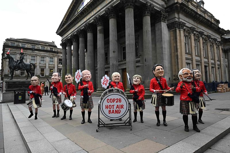 Oxfam activists dressed as a Scottish pipe band and representing (L-R) Russian president Vladimir Putin, Italian prime minister Mario Draghi, French president Emmanuel Macron, US president Joe Biden, British prime minister Boris Johnson, Germany's chancellor Angela Merkel, Canadian prime minister Justin Trudeau, India's prime minister Narendra Modi and Chinese president Xi Jinping pose during their "Big Heads" protest stunt at the Royal Exchange Square in Glasgow on 1 November 2021 on the sidelines of the COP26 UN Climate Summit.