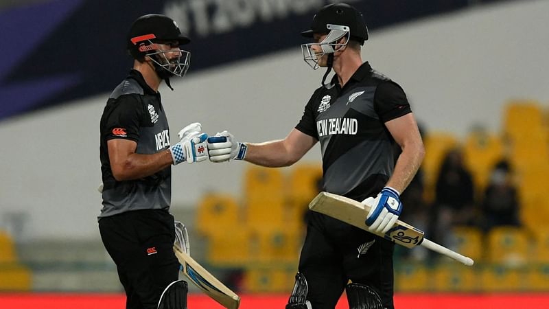 New Zealand's James Neesham (R) and Daryl Mitchell bump their fists after a six during the ICC men’s Twenty20 World Cup semi-final match between England and New Zealand at the Sheikh Zayed Cricket Stadium in Abu Dhabi on 10 November, 2021