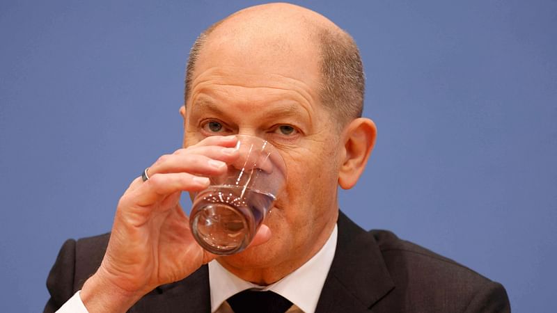 Designated German Chancellor Olaf Scholz drinks during a press conference following a signing ceremony in Berlin on 7 December 2021, where leading members of Germany's social democratic SPD party, the Greens and the free democratic FDP party sealed their coalition deal to form a new government