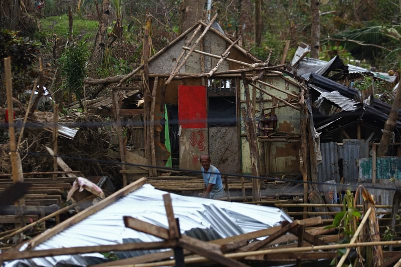 A resident gathers wood as he tries to fix his damaged house in Surigao City, Surigao del Norte province, on 24 December, 2021