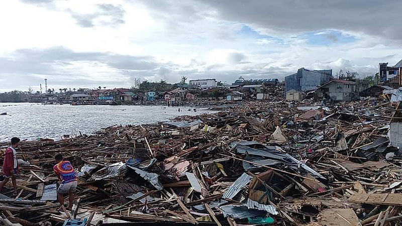 In this photo taken on 17 December, 2021, residents trie to salvage belongings next to destroyed houses along the coast in Ubay town, Bohol province, in central Philippines, a day after super Typhoon Rai devastated the town