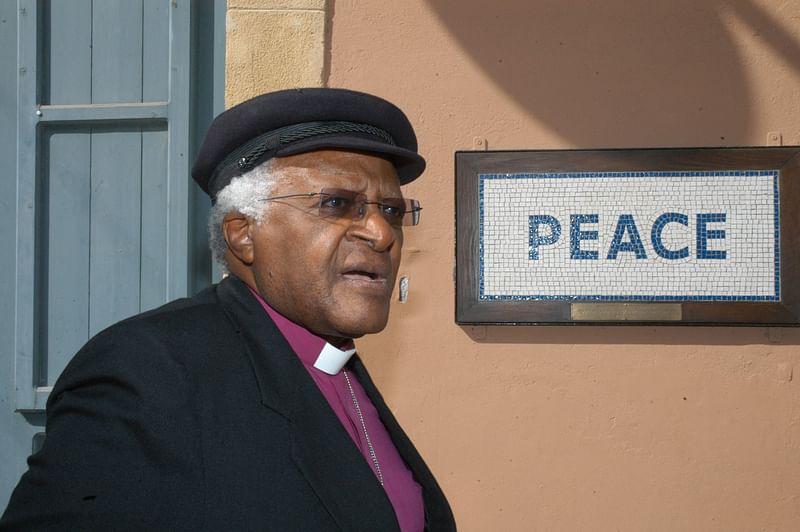 In this file photo taken on 9 October 2008 South African cleric and anti-apartheid campaigner Desmond Tutu walks past a street mosaic which reads 'Peace' on the green line that separates the Greek Cypriot side from the Turkish military-controlled areas in the heart of Nicosia