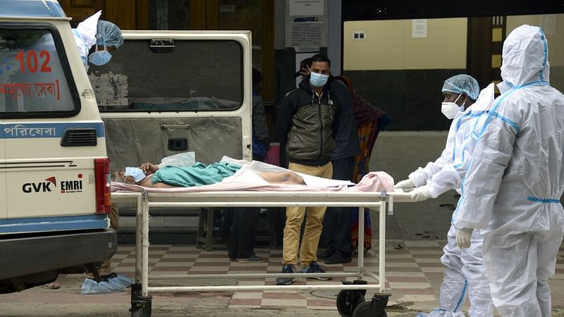 Healthcare workers carry a Covid-19 infected patient on a stretcher for treatment at a hospital, in Kolkata on 14 January 2022