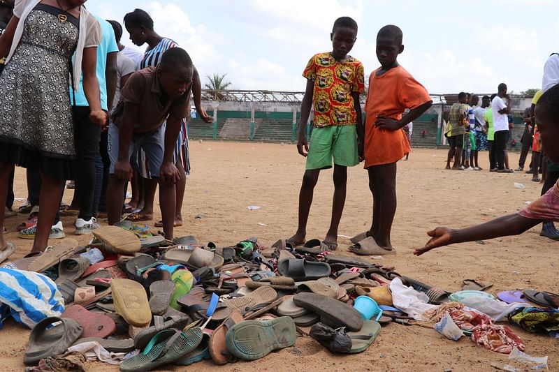 People search through piles of shoes left at a field in Monrovia, on 20 January, 2022, where 29 people, including a pregnant woman and 11 children are confirmed dead after a stampede broke out at a Christian crusade on the night of 19 January, 2022