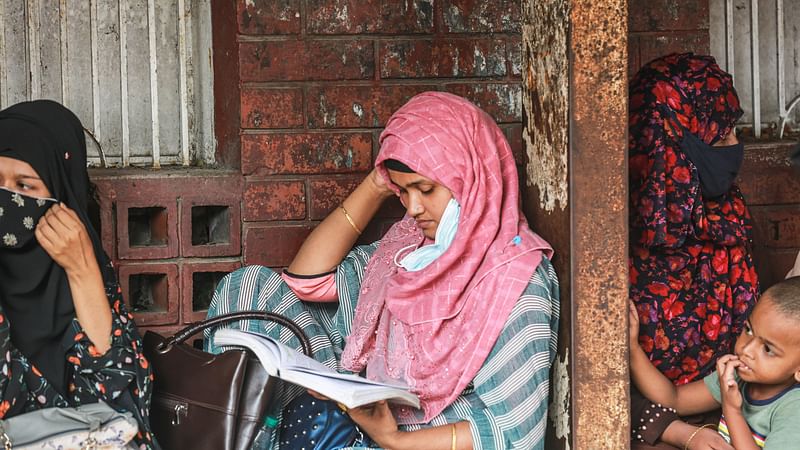 As the husband (not in picture) sits for an hour-long recruitment test, Sonia Zaman (M) also takes preparation for job while waiting outside the test centre. The picture was taken from Mirpur Girls Ideal Collage in Dhaka on 17 January 2021.