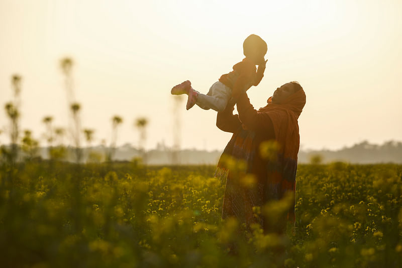 A mother adores her baby in the midst of a mustard field with the last sunset of 2021 in west sky. The picture was taken from Sirajdikhan in Munshiganj on 31 December.