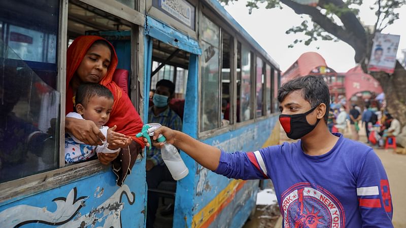 A transport worker sanitizes a child's hands on a public bus amid the coronavirus disease (Covid-19) outbreak in Dhaka, Bangladesh, 22 June 2020