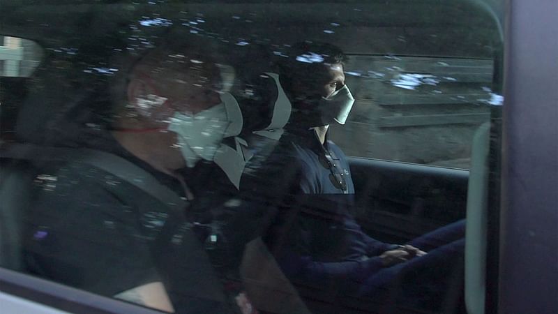 his screen grab taken from AFPTV shows Serbia's Novak Djokovic (R) wearing a face mask as he arrives at the Lawyer's office ahead of the Australian Open tennis tournament in Melbourne on 16 January, 2022